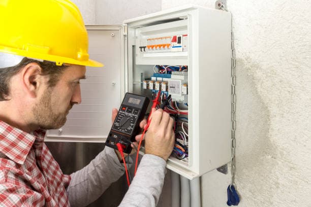 A person looking at an electricity meter on the wall of a property