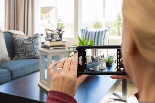 A person taking photos of a room with their phone on the day they move into a new rental