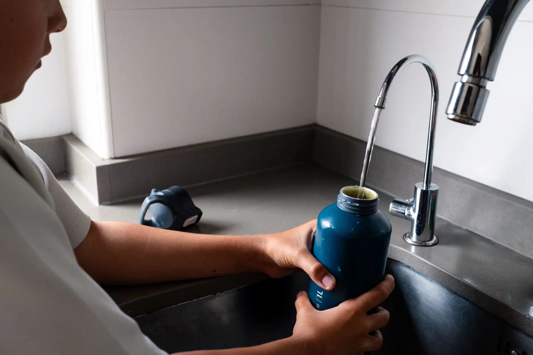 A person turning on a kitchen tap to test the water pressure during a house viewing