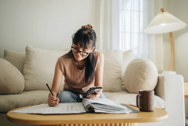 A person sitting at a desk going through their monthly budget and expenses