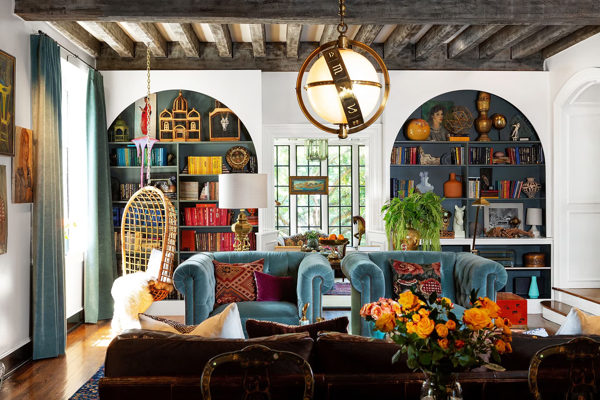 A colorful bohemian living space with hanging plants, patterned cushions, and layered woven rugs