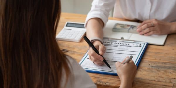 Someone sitting at a table reading through a lease agreement before signing it