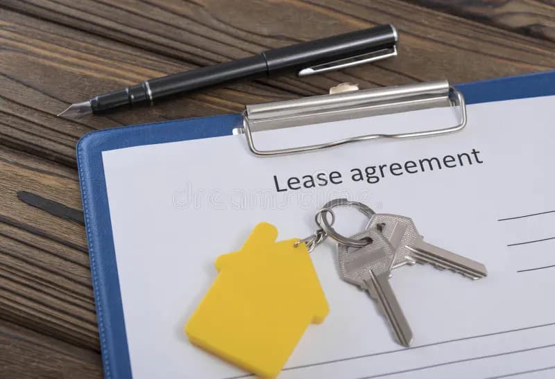 A signed lease contract and house keys on a wooden desk