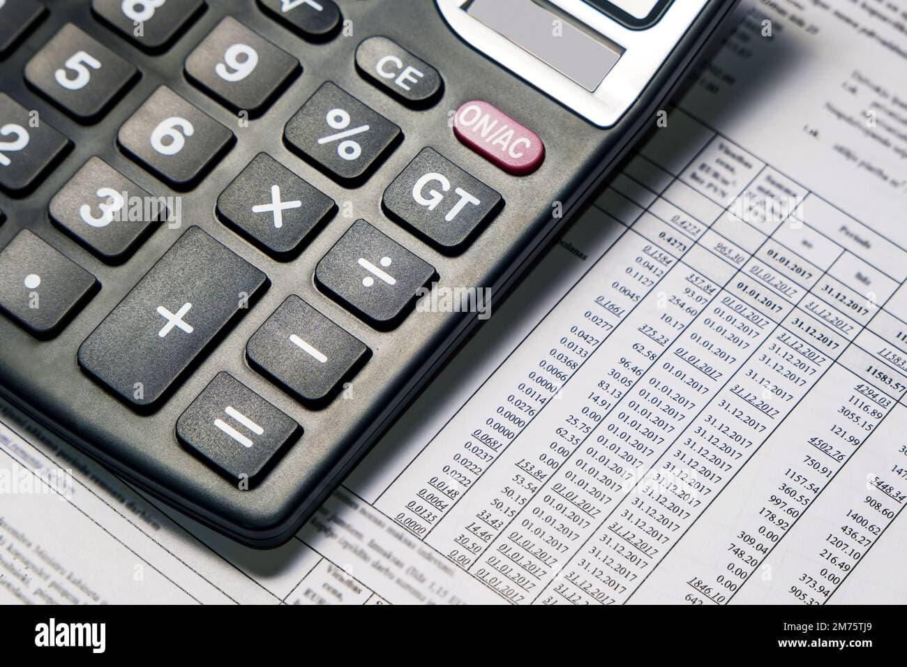 Utility bills and expense papers spread on a table with a calculator